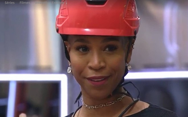 Karol olha para frente, usa capacete vermelho e sorri