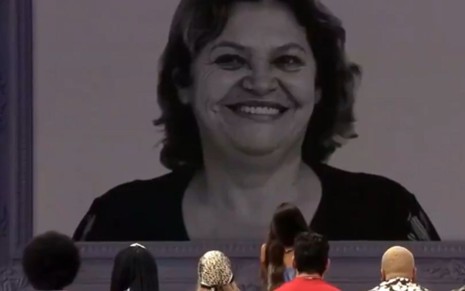 Imagem de participantes do BBB21, de costas, olhando a foto de Fátima Freire, mãe de Juliette Freire, no telão