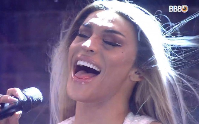 Pabllo Vittar está segurando um microfone, está com a boca aberta e olhos fechados