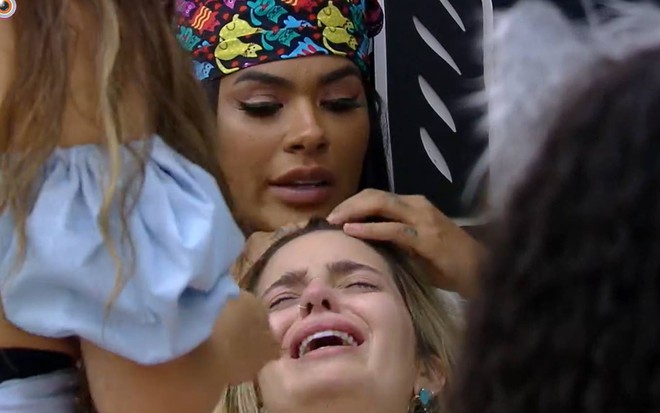 Viih Tube está deitada, olha para cima, chora e está com a boca aberta; Pocah olha para a sister e está com bandana na cabeça