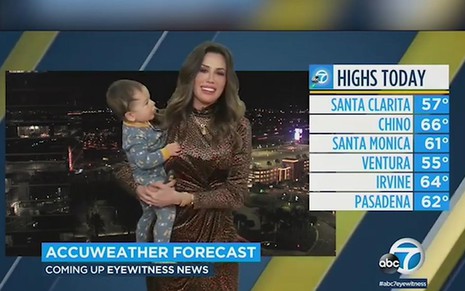 Leslie Lopez com sorriso sem graça segurando o filho Noan no colo em transmissão ao vivo