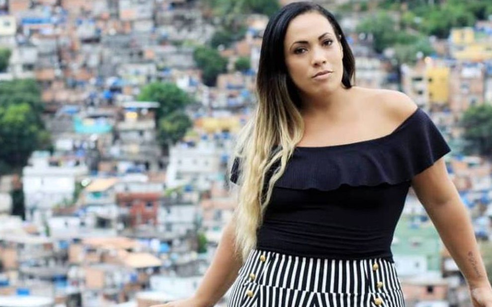 Fabiana Escobar, conhecida como Bibi Perigosa, posa séria para foto com Rocinha ao fundo