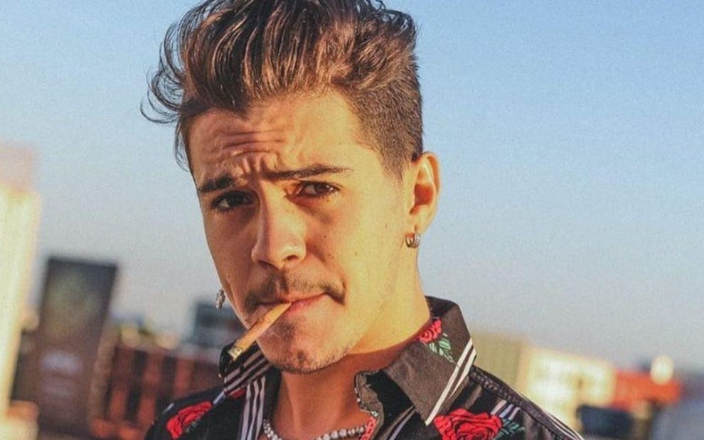 Imagem de Biel com uma camisa estampada e fumando um cigarro