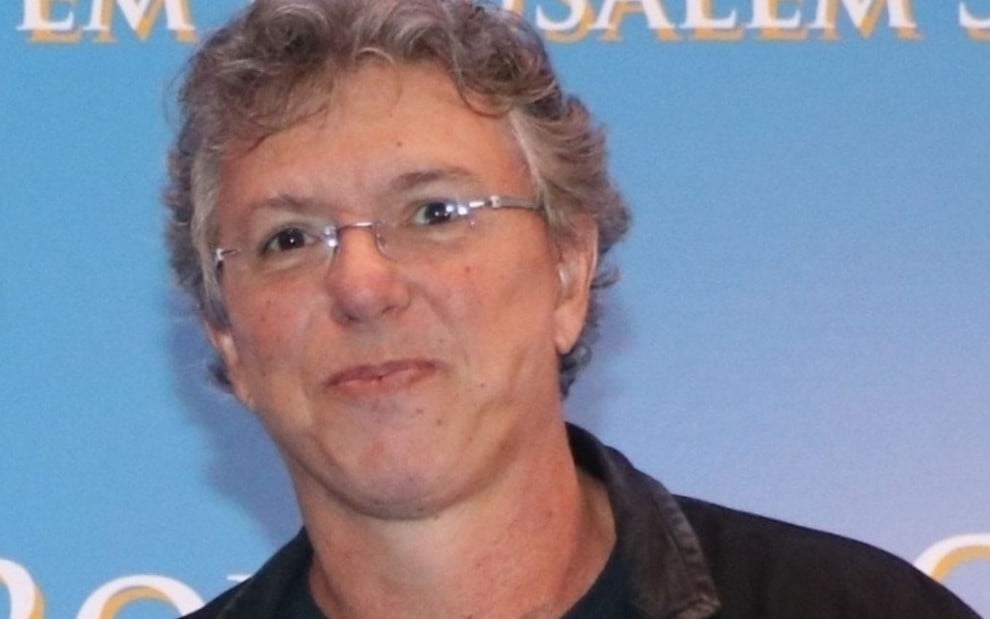 Imagem de Boninho, diretor da Globo, em frente a um fundo azul