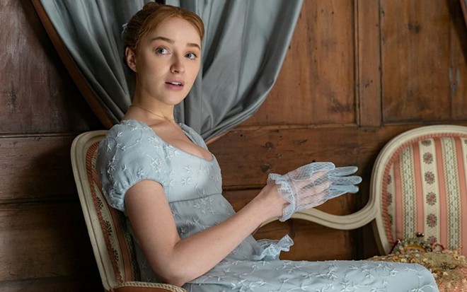 Phoebe Dynevor sentada em cena da primeira temporada de Bridgerton