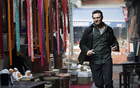 Liam Neeson como o ex-agente da CIA Bryan Mills em Busca Implacável, ele corre no meio de um mercado popular de Istambul na Turquia