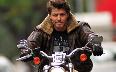 O modelo e ex-BBB Caetano Zonaro posa para foto dirigindo uma moto, com jaqueta de couro