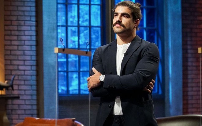Caio Castro de terno olhando para o lado em participação no reality Shark Thank Brasil
