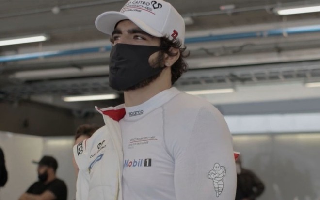 Imagem de Caio Castro com macacão de piloto, boné e máscara