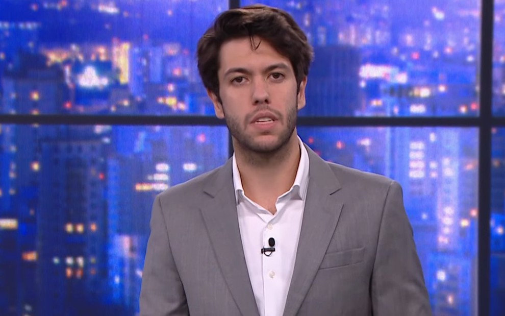 Caio Coppolla descabelado vestindo terno cinza na bancada de um quadro de debates na CNN Brasil