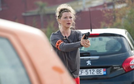 Cécile Bois persegue bandido com arma em mãos em cena da série francesa Candice Renoir