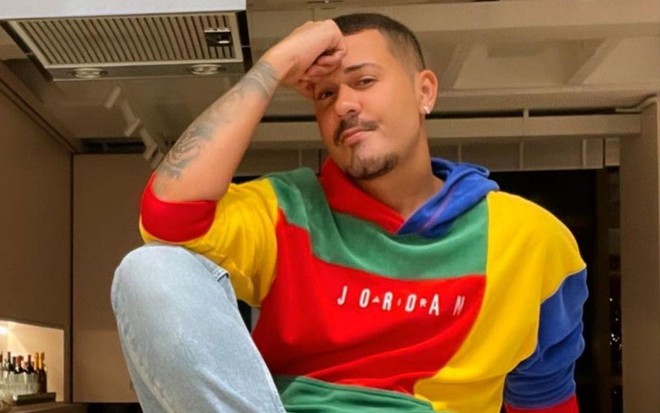 Carlinhos Maia em foto publicada no Instagram, com uma blusa colorida e o braço apoiado no joelho