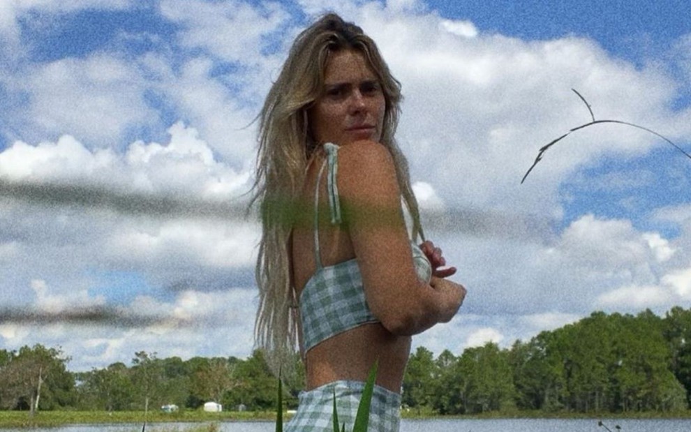 Carolina Dieckmann de biquíni em foto publicada no Instagram; a atriz aparece fazendo pose na beira de um rio