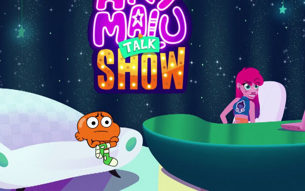 Darwin, de O Fantástico Mundo de Gumball, está sentado em um sofá branco, enquanto Any Malu está na bancada de seu talk show no Cartoon Network