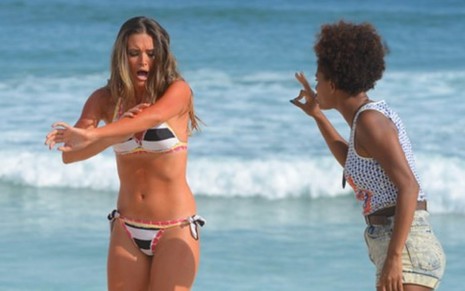 Na praia, Cassandra (Juliana Paiva) grita ao ver que está queimada demais enquanto leva uma bronca de Adele (Jéssica Ellen)