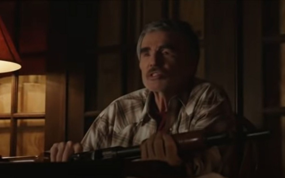 Burt Reynolds segura uma arma em cena do filme Categoria 5