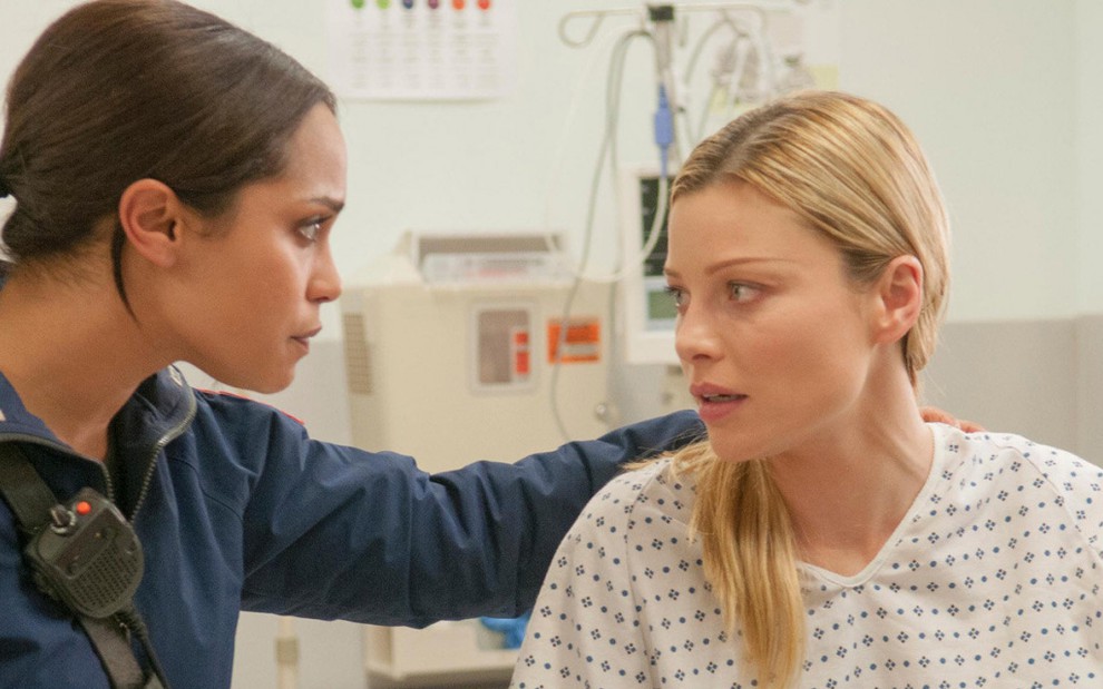Com unifome de paramédica, Monica Raymund consola Lauren German, com avental de paciente, na série Chicago Fire