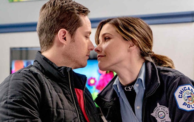 Com uniforme de policial, Sophia Bush inclina o rosto para beijar o loiro Jesse Lee Soffer em cena de Chicago P.D.