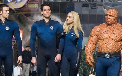 Com uniformes azuis, Chris Evans, Ioan Gruffudd, Jessica Alba e Michael Chiklis caminham na rua em cena de Quarteto Fantástico (2005)