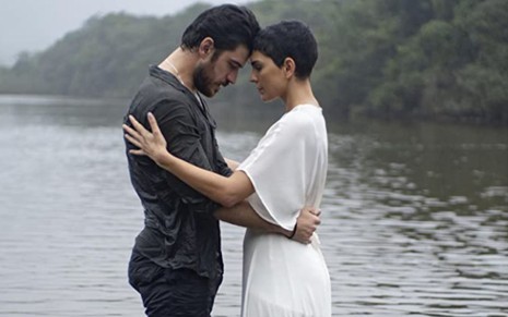 Marco Pigossi e Julia Konrad se entrelaçam por cima de um rio em cena da série Cidade Invisível