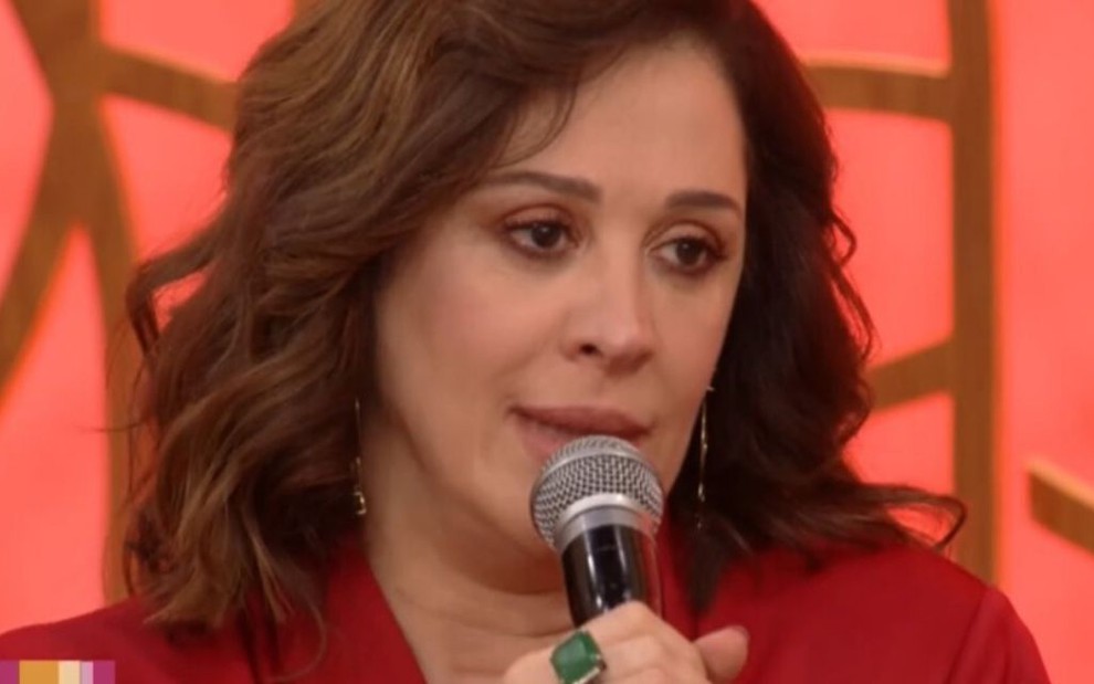 Claudia Raia segura o microfone no cenário do Encontro em 2019