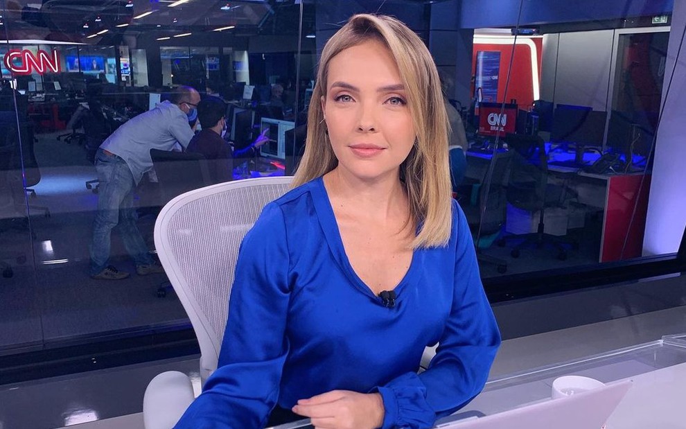 De blusa azul, Taís Lopes aparece séria na bancada da CNN Brasil