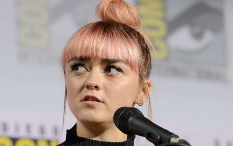Com cabelo rosa amarrado em forma de coque, a atriz Maisie Williams faz cara de chateada na Comic-Con 2019