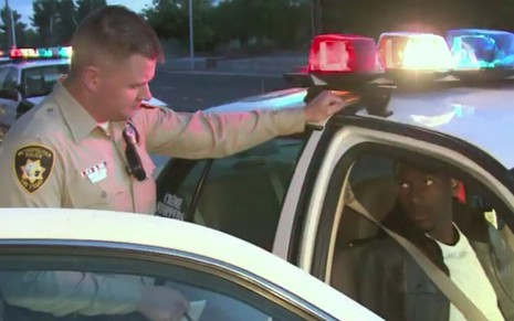 Policial branco da cidade de Las Vegas conversa com um homem negro detido, dentro de uma viatura, em cena do programa Cops
