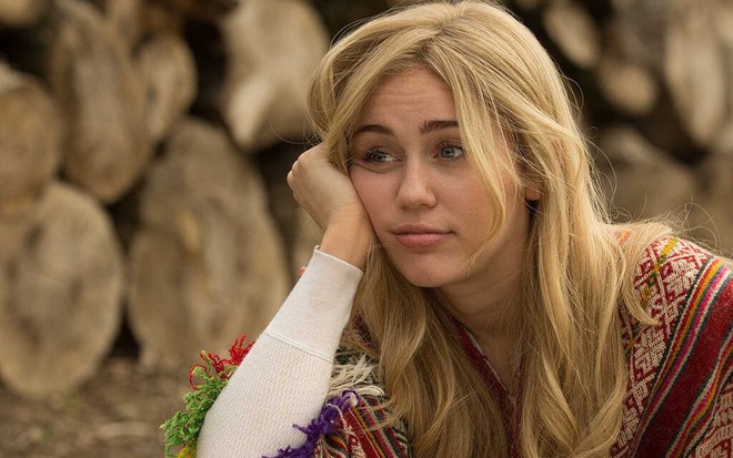 Loira, Miley Cyrus aparece entediada, com a mão direita no rosto, em cena da série Crisis in Six Scenes