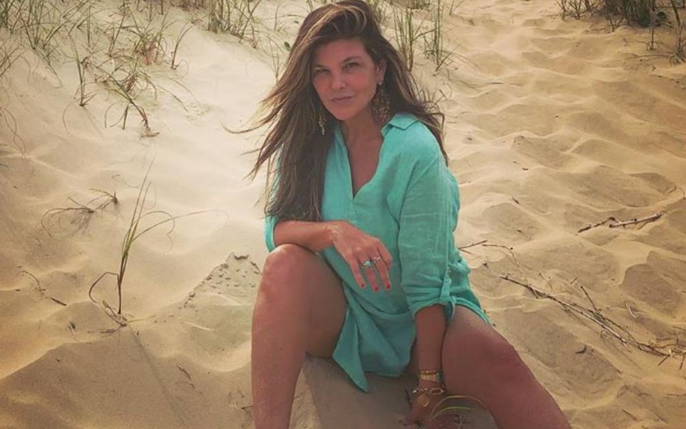 Cristiana Oliveira posa para foto numa praia com vestido verde e expressão séria