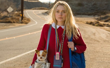Dakota Fanning caminha por uma rodovia, ela carrega um cachorrinho dentro de uma bolsa em cena de Tudo que Quero (2018)