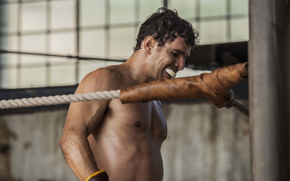 Daniel de Oliveira sem camisa, no ringue, olhando para baixo e usando um protetor bucal