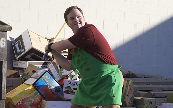 Com o uniforme de atendente de mercado, Produce (David DeSanctis) segura um taco de beisebol em cena de Onde Nasce a Esperança (2014)
