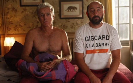 Franck Dubosc e Kad Merad tristes e sentados na cama em cena de De Volta para o Passado (2015