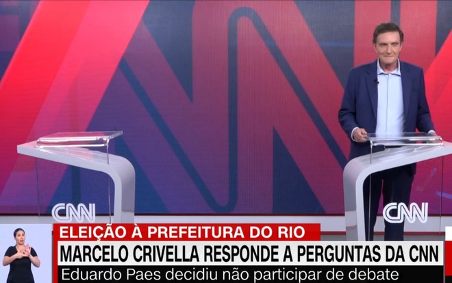 Imagem de Marcelo Crivella nos estúdios da CNN Brasil ao lado de um púlpito vazio devido a ausência de Eduardo Paes