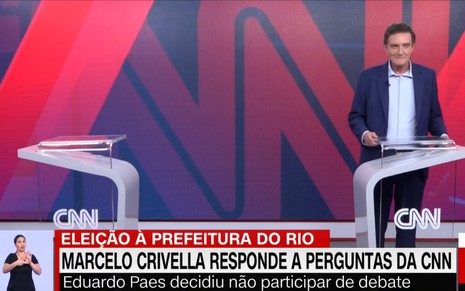Imagem de Marcelo Crivella nos estúdios da CNN Brasil ao lado de um púlpito vazio devido a ausência de Eduardo Paes