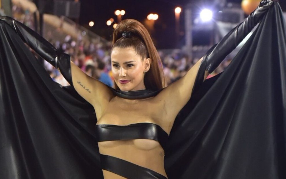Deborah Secco coberta por fitas pretas e com uma capa na Marquês de Sapucaí, no Rio de Janeiro