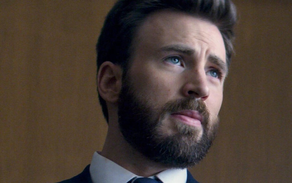 Com sua barba impecavelmente bem feita, Chris Evans entra em um tribunal na série Defending Jacob