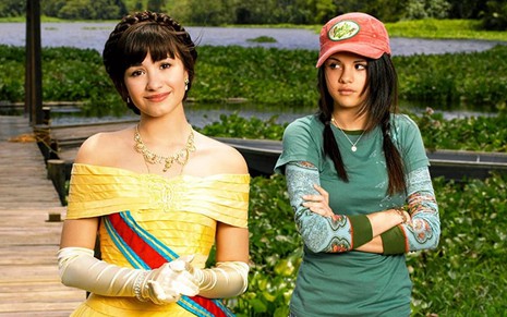 Demi Lovato (como princesa, com um vestido amarelo) e Selena Gomez (com cara de marrenta, usando boné e camiseta) em Programa de Proteção para Princesas