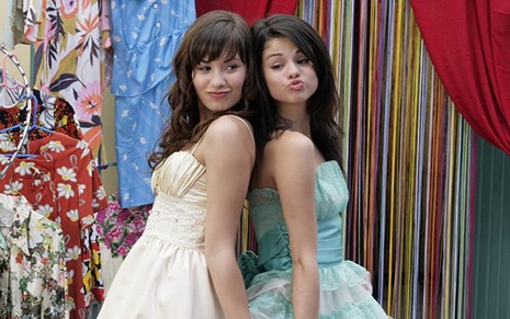 Demi Lovato e Selena Gomez provam vestidos de festa em cena do filme Programa de Proteção para Princesas