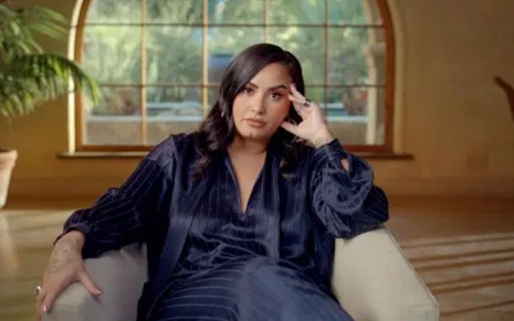 Demi Lovato sentada em uma poltrona em cena do documentário Demi Lovato: Dancing With the Devil