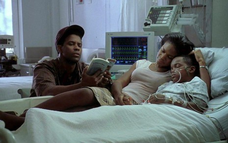 Denzel Washington lê um livro, enquanto Kimberly Elise está abraçada junto de Daniel E. Smith em uma cama de hospital