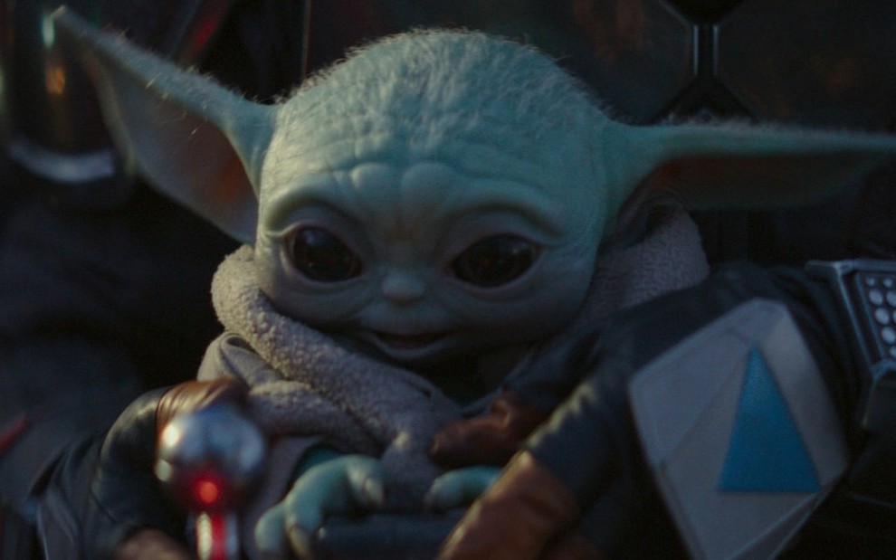Baby Yoda esbanja fofura no colo do personagem principal de The Mandalorian