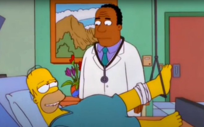 O personagem Dr. Hibbert, com jaleco e estetoscópio, conversa com Homer Simpson, deitado em cama de hospital