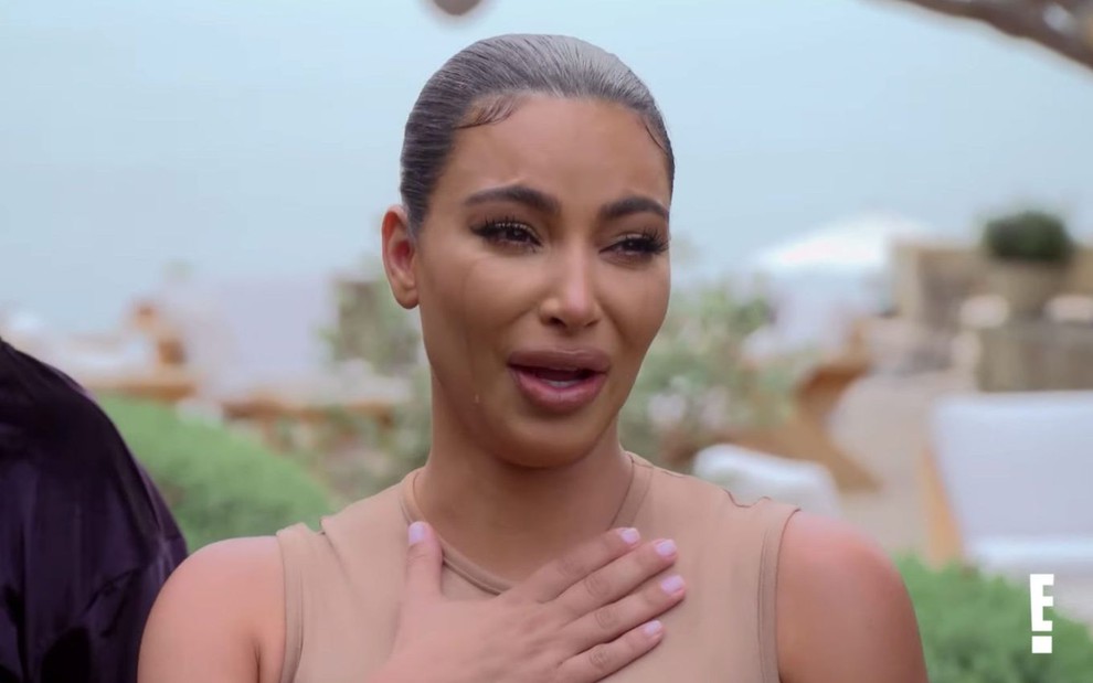 Kim Kardashian chora com a mão no peito em cena de Keeping Up With the Kardashians