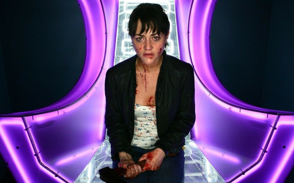 A atriz Jamie Winstone, com machado nas mãos e coberta de sangue, em cena da minissérie Dead Set, do canal E4