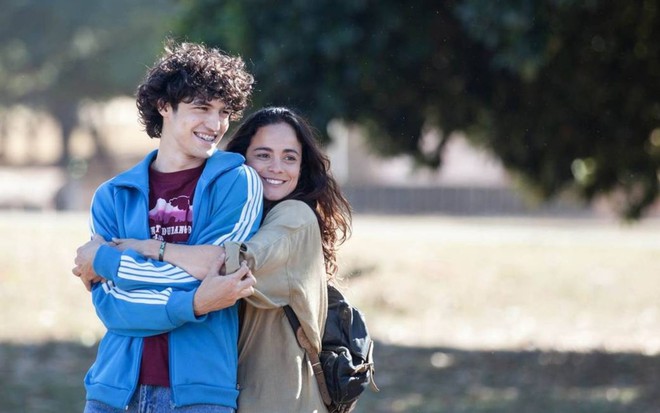 Os atores Gabriel Leone e Alice Braga abraçados e sorrindo em cena como os protagonistas do filme Eduardo e Mônica