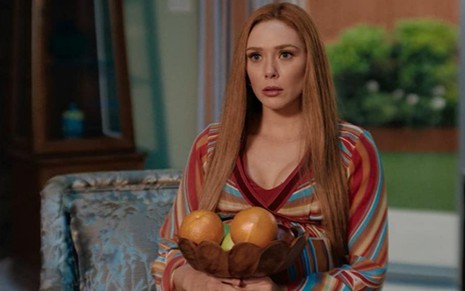 Elizabeth Olsen segura uma cesta de frutas em cena do terceiro episódio da série WandaVision