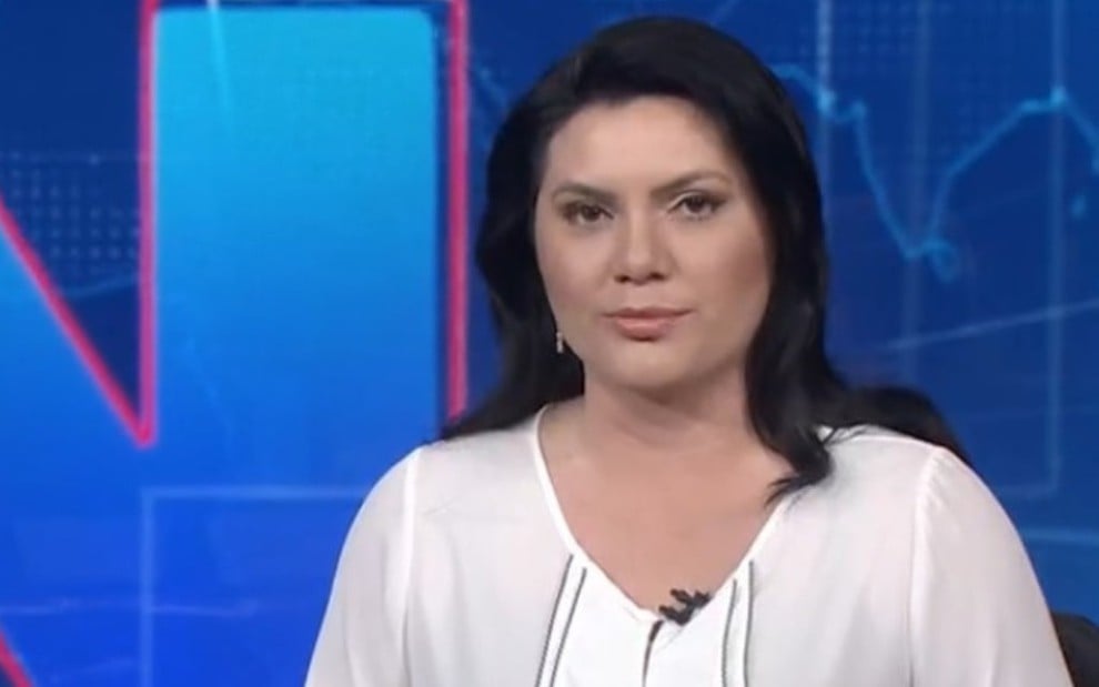 Com expressão séria, a jornalista Ellen Ferreira usa uma blusa branca e cabelos pretos soltos na bancada do Jornal Nacional