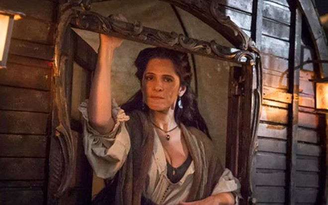 A atriz Ingrid Guimarães vestida com roupas de época em um navio pirata em cena da novela Novo Mundo